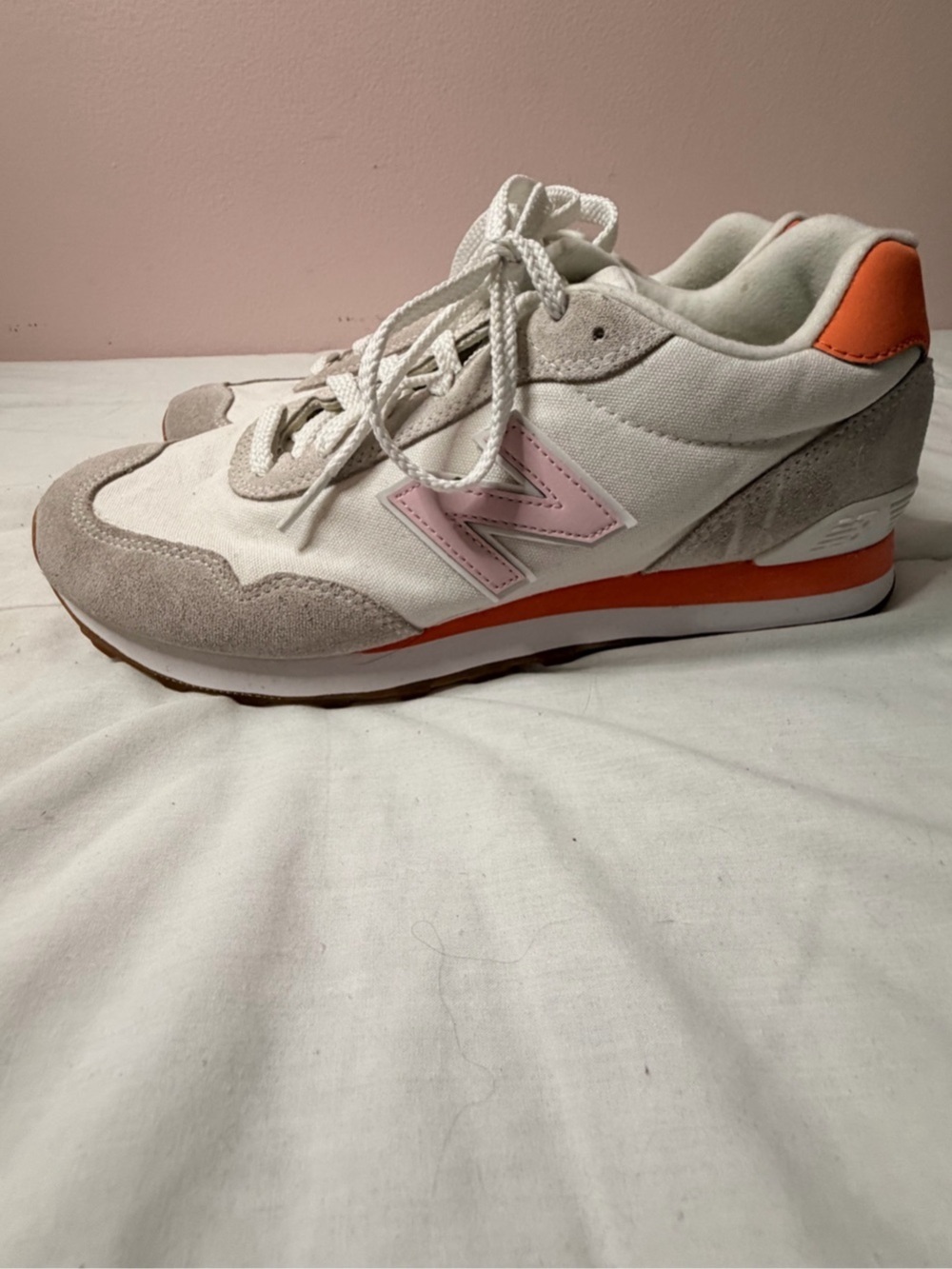 New Balance 574 women’s sneakers in a white, pink and orange colorway.